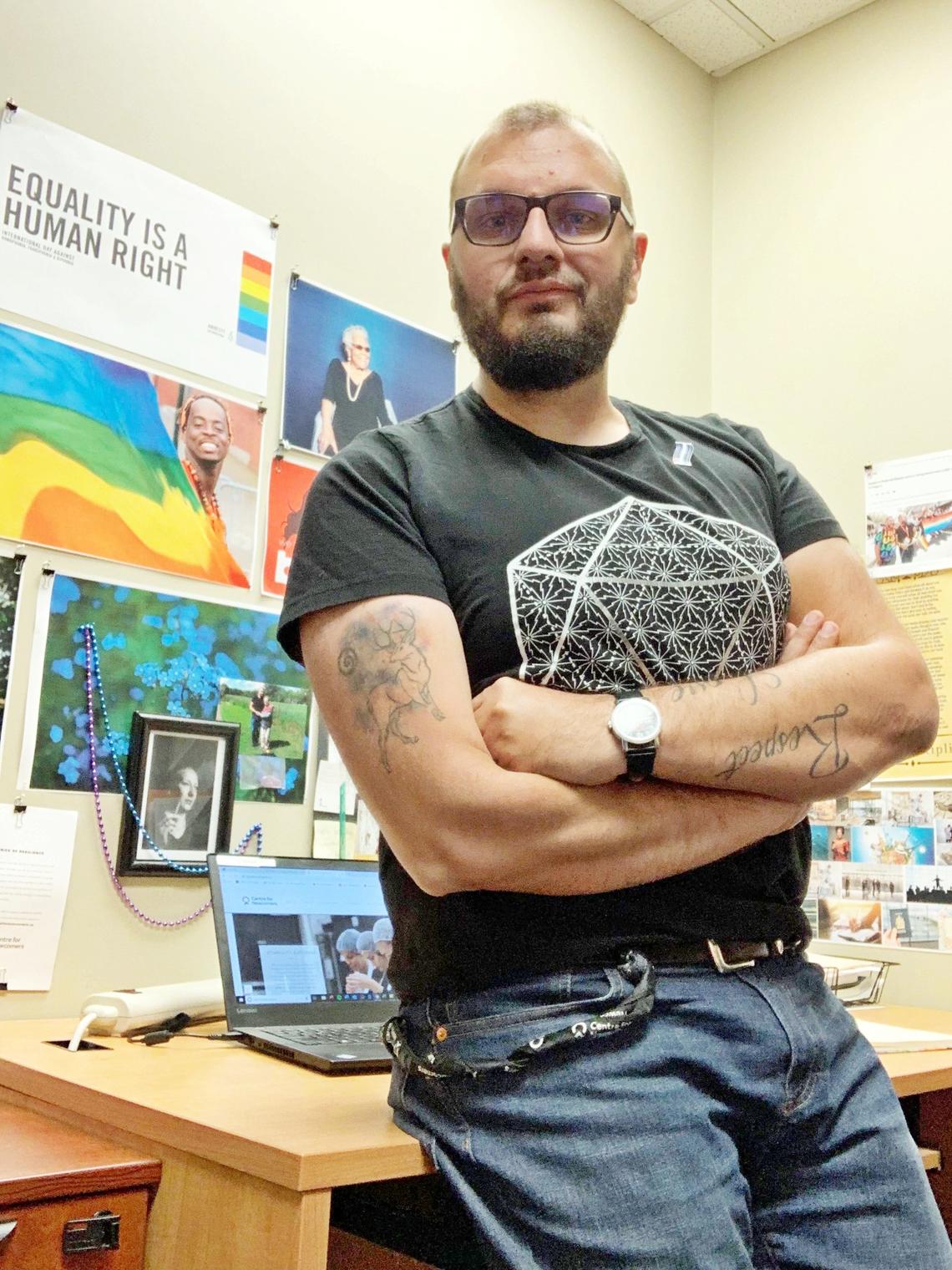 man leaning on desk with posters in background