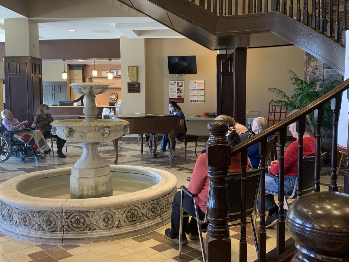 Woman plays piano at Tudor Manor