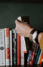 Hand grabbing a book from a bookshelf