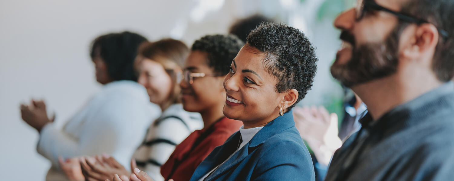 A seated crowd of mixed ethnicity clapping 