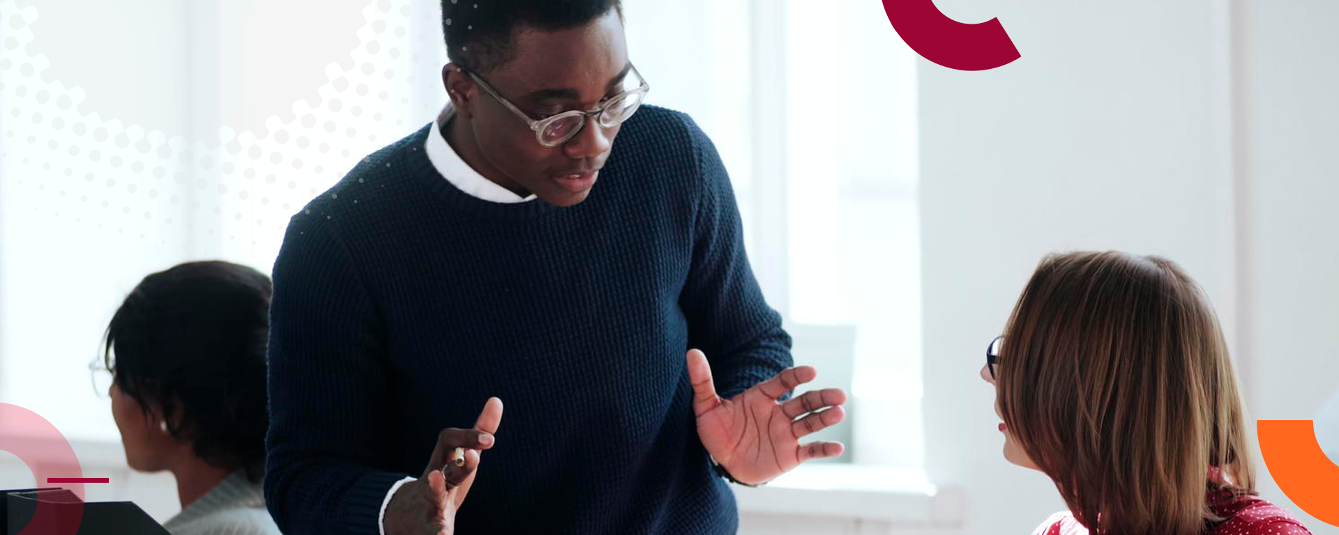 Standing man speaking to a seated colleague image promoting the university of Calgary Faculty of Social Work professional Development Programs