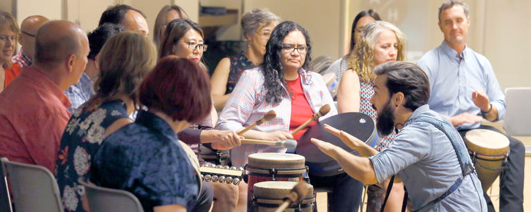 Faculty members participate in a drum circle during a faculty retreat