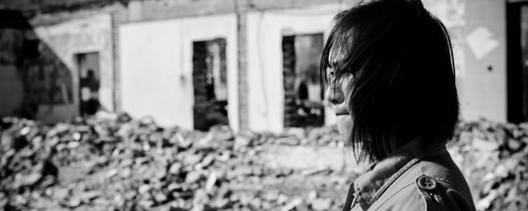 A woman surveys devastation caused by conflict