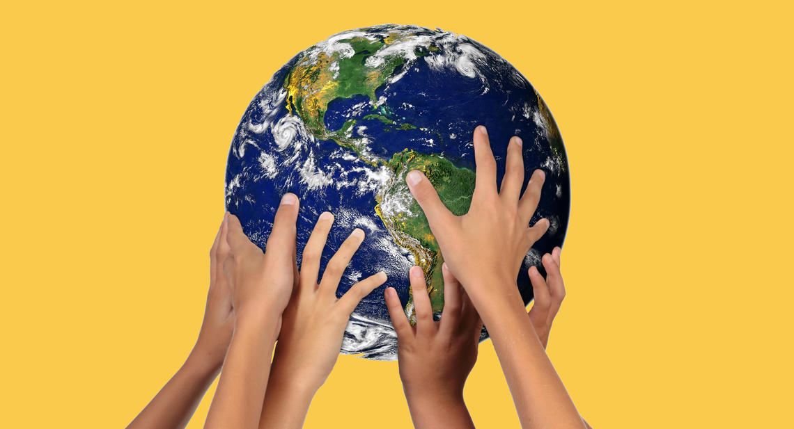 Children's hands holding up a globe