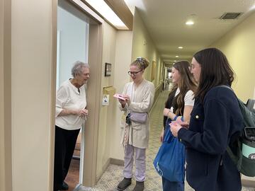 Larissa Mohler, Sarah Park and Jenna Perna from the BSW Calgary BSW program delivering a card to a resident of Chartwells Royal Park Retirement Residence