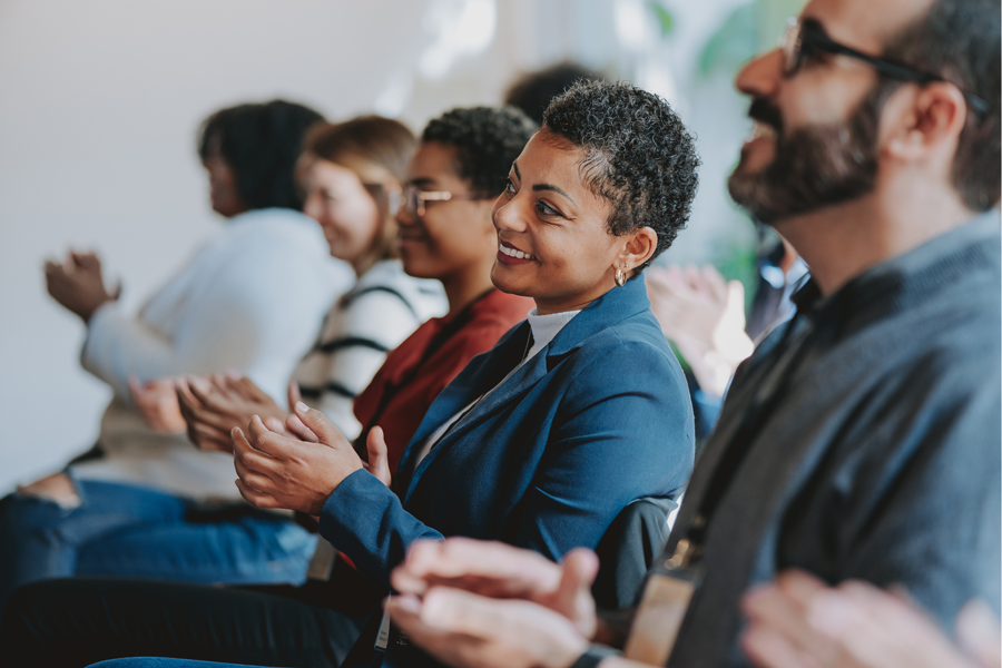 A seated crowd of mixed ethnicity clapping 